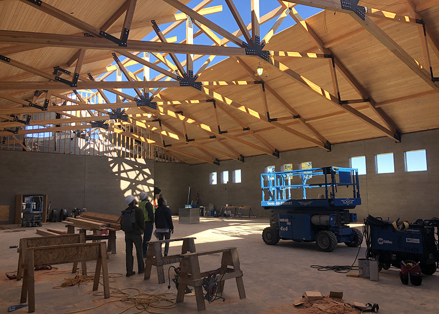 the interior of the Gymnasium. The roof is complete but for a strip along the center that still needs to cedar Nail-lamintated-timber panels that adorn the rest of the ceiling